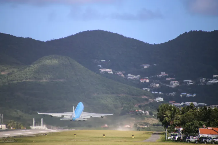 Airliner taking off from Saint-Martin airport with the green hills behind