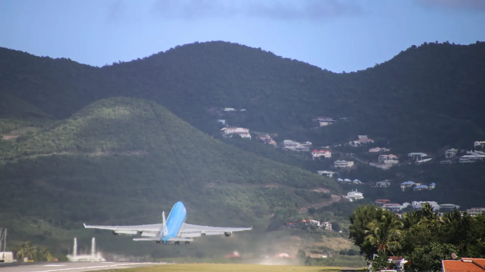 Airliner taking off from Saint-Martin airport with the green hills behind